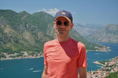 Man standing on a viewpoint above the Bay of Kotor with dramatic mountains and blue Adriatic waters in the background